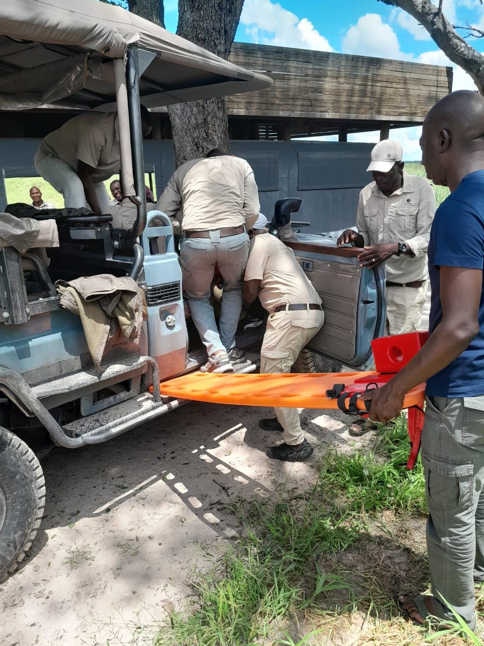 Lodge staff extracting a casualty from a safari vehicle onto an orange spineboard during Cardio Life training