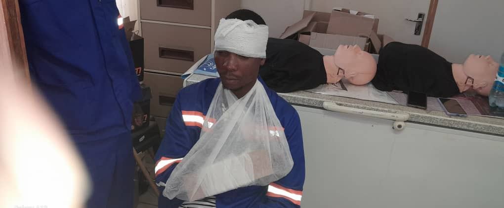 First aid learner with head bandage and arm sling beside CPR manikins in a Cardio Life classroom session