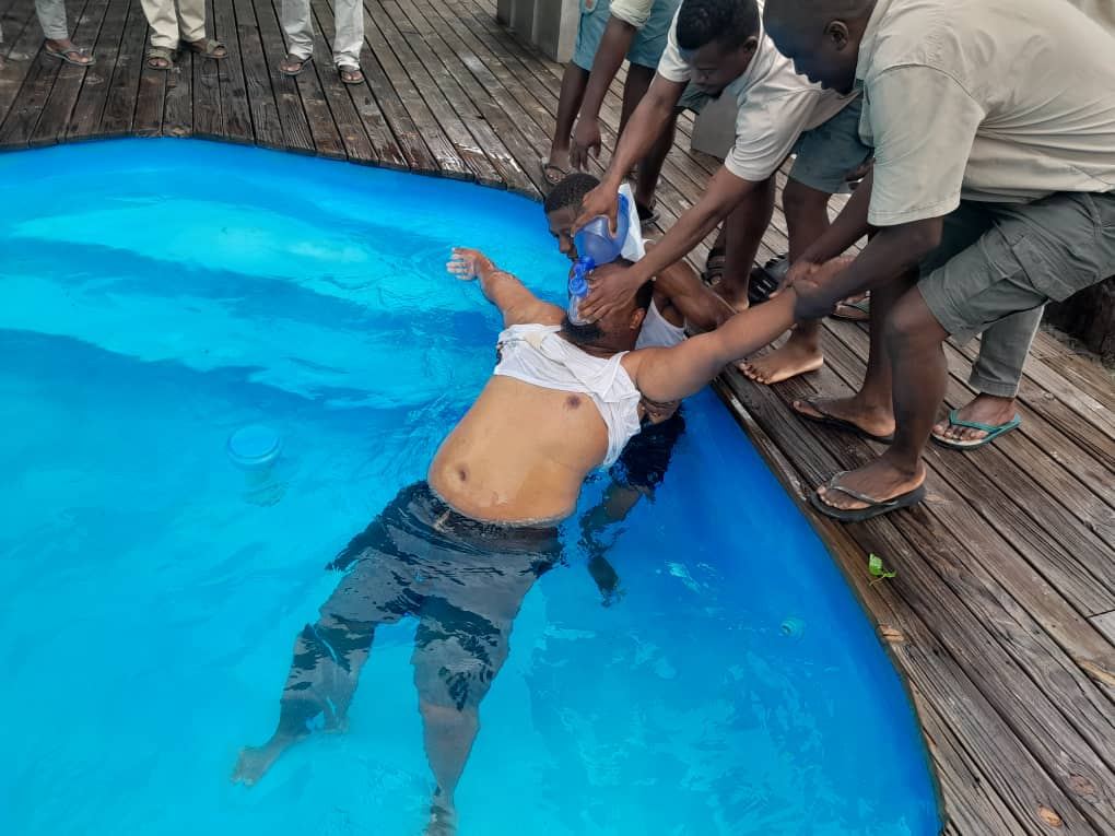 Cardio Life aquatic rescue drill — lodge staff supporting a casualty with rescue breathing in a swimming pool, Okavango Delta